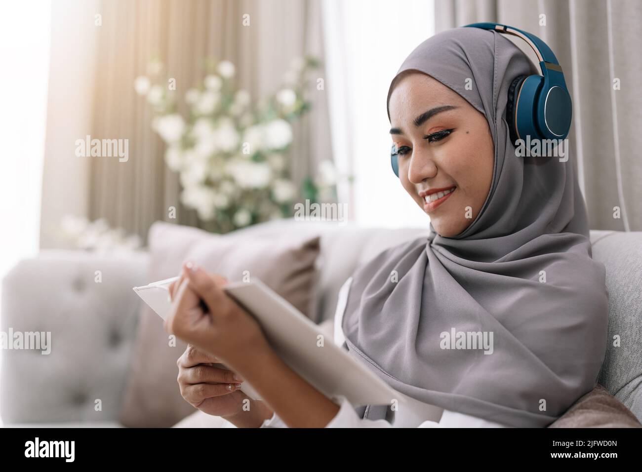 Cozy stay at home activities. young woman in hijab reading her favorite ...