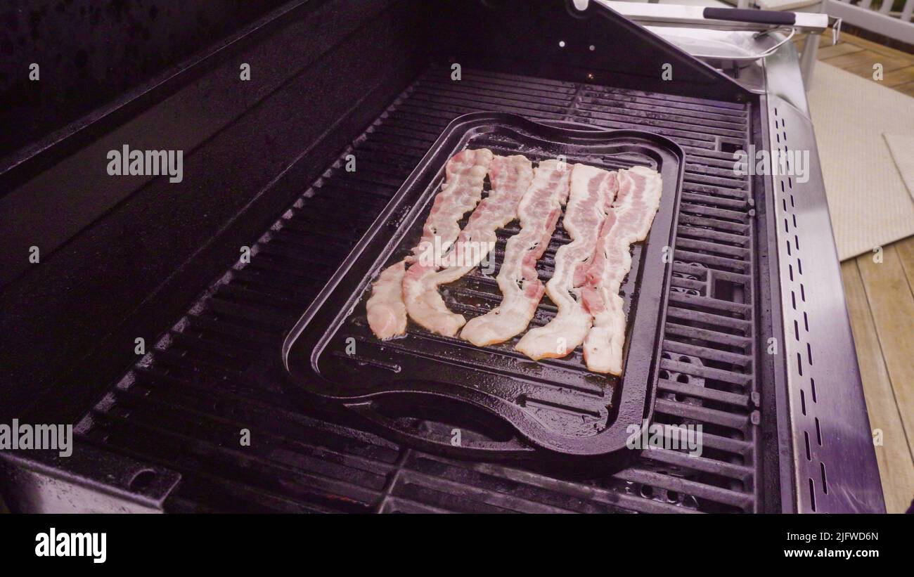 Cooking bacon stips on an outdoor gas grill Stock Photo Alamy