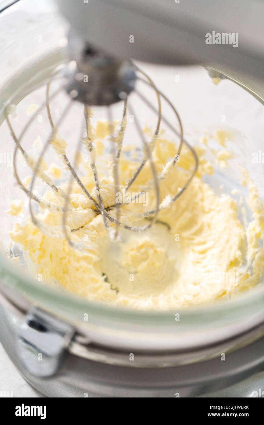 Whipping strawberry buttercream frosting in a standalone electric mixer with a whisk attachment