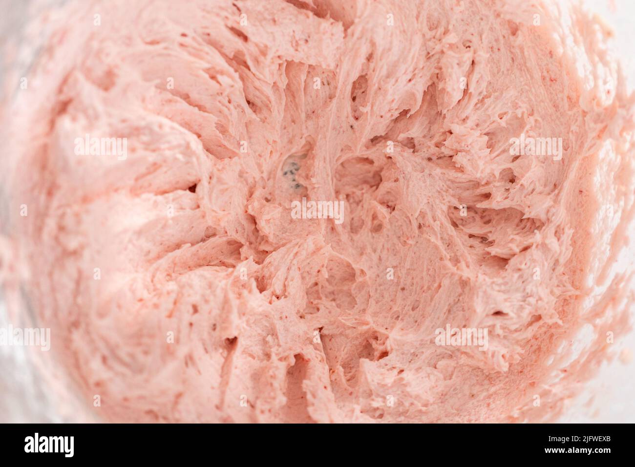 Whipping strawberry buttercream frosting in a standalone electric