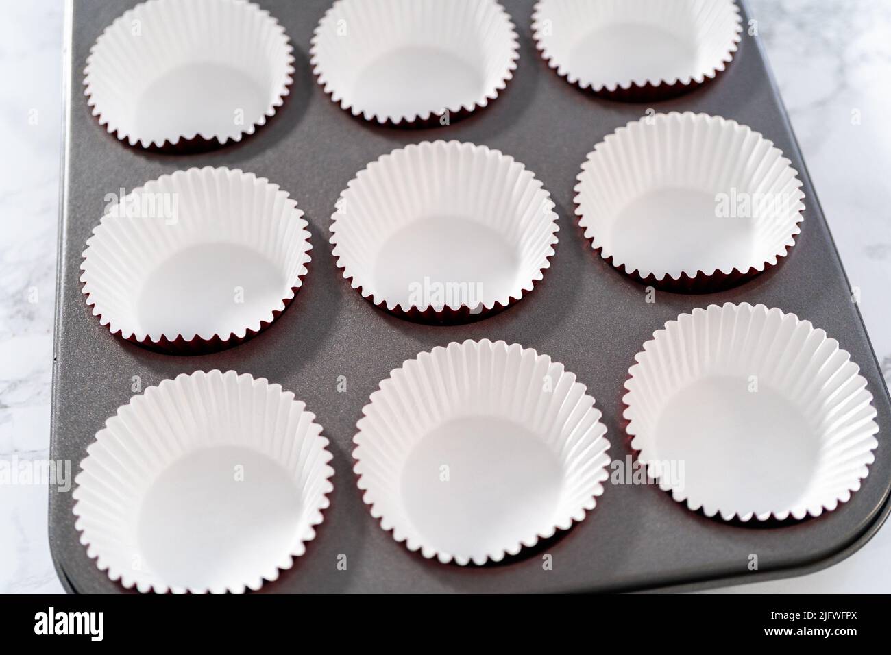 Lining cupcake pan with foil cupcake liners to bake red velvet cupcakes