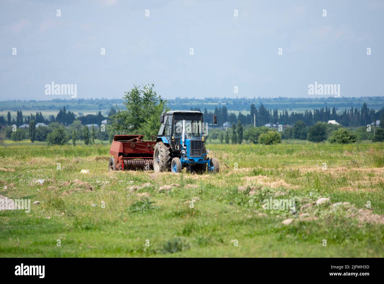 An old soviet tractor working in a field in Kyrgyzstan. Stock Photo