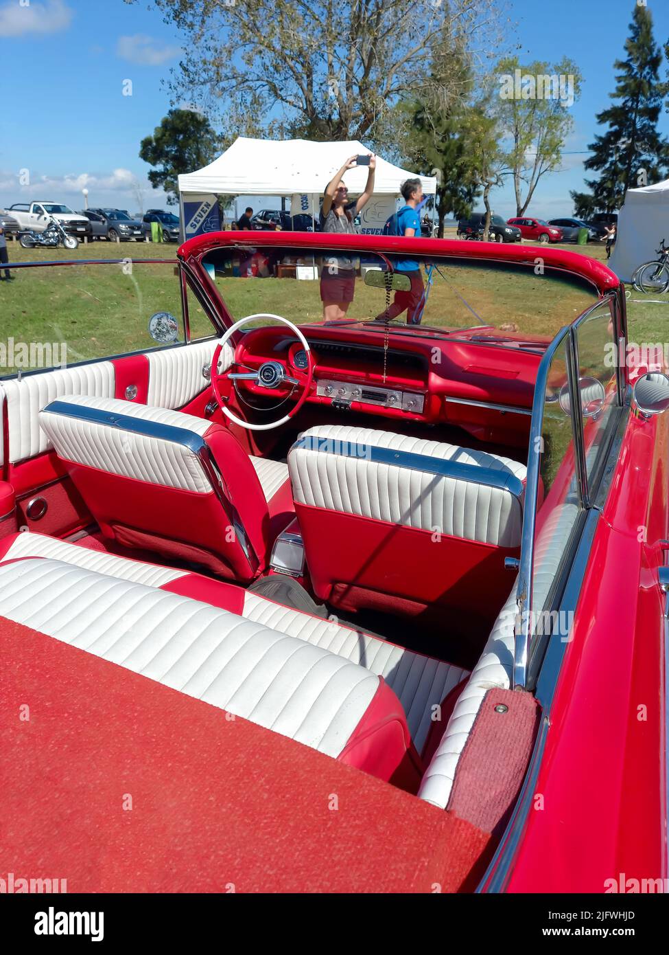 Red and white interior of old Chevrolet Chevy Impala SS Super Sport V8 convertible 1964 in the countryside. Nature grass and trees. Classic car show Stock Photo