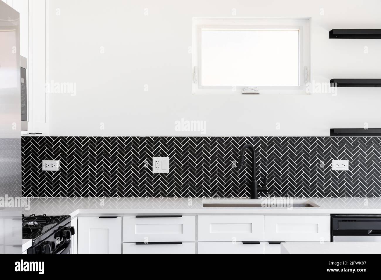 A kitchen sink detail shot with a black faucet, black marble