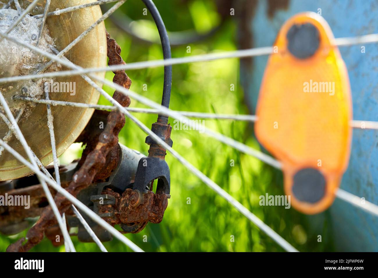 Close up of an old rusty bicycle. Drive chain is broken. Reflector on