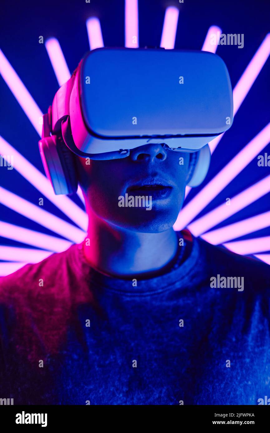 Futuristic vertical portrait of young man wearing VR headset with neon ...