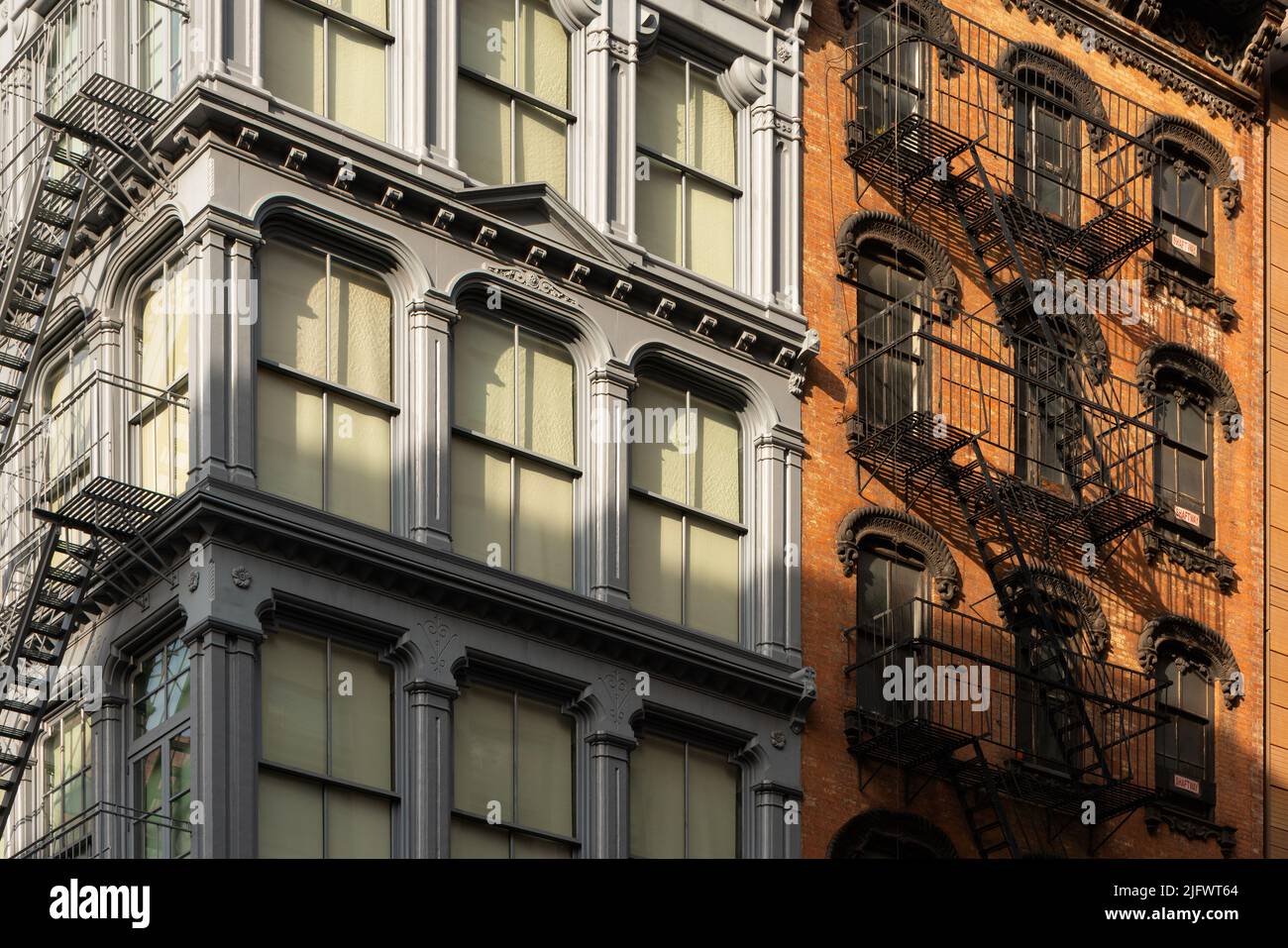 Cast iron and brick facades of Soho loft buildings with fire escapes at sunset. Soho Cast Iron Building Historic District, Manhattan, New York City Stock Photo