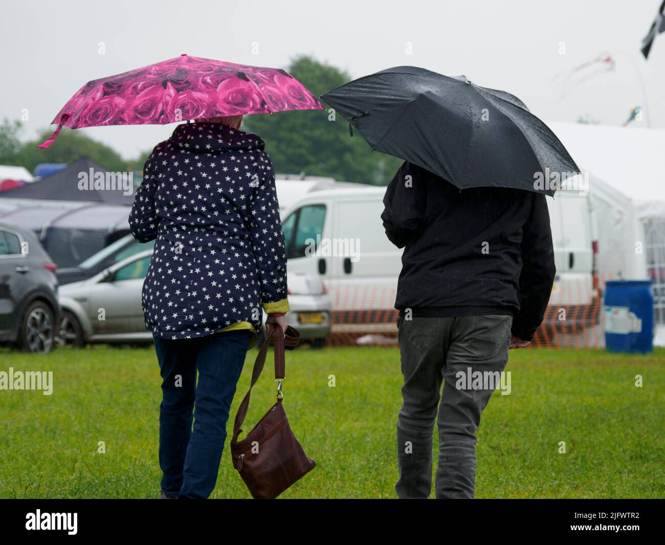 Couple with umbrellas in the rain at the Launceston Steam & Vintage Rally, Cornwall, UK Stock Photo