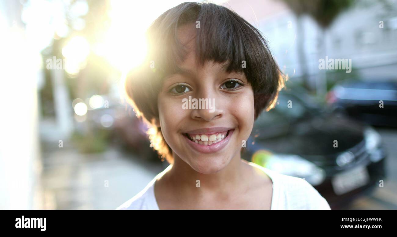 Handsome mixed race child portrait smiling. Beautiful closeup ethnically diverse boy outside in