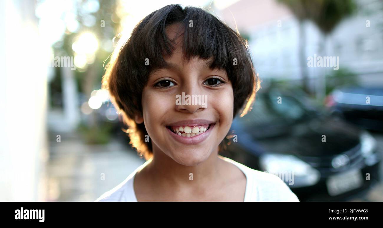 Handsome mixed race child portrait smiling. Beautiful closeup ethnically diverse boy outside in