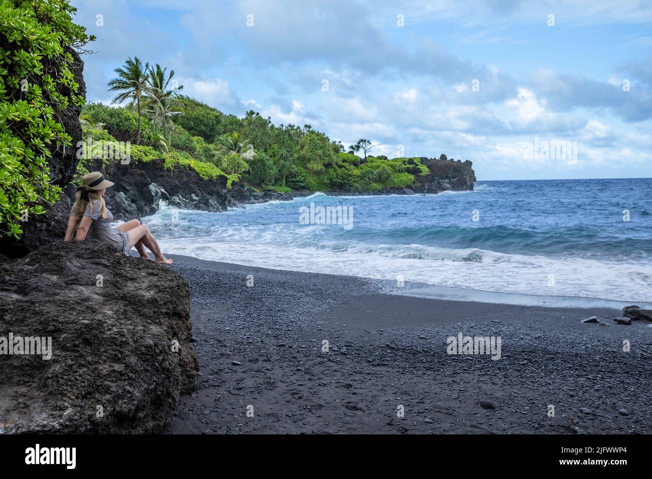 A model at the black sand beach at Waianapanapa State Park, Hana, Maui, Hawaii. Stock Photo