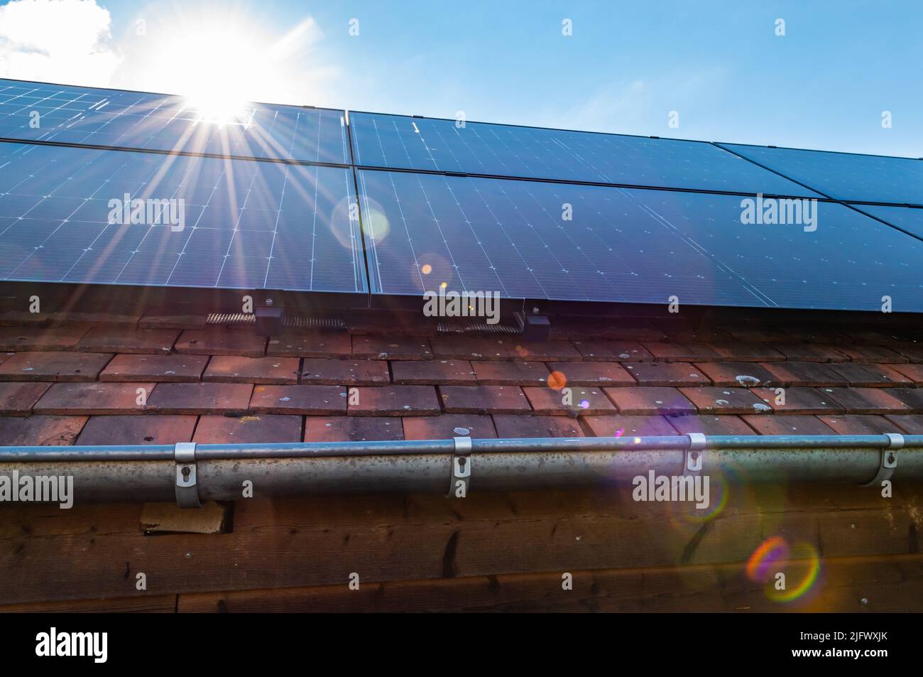 Sun rays shine on roof with solar panels. Renewable energy concept. Stock Photo