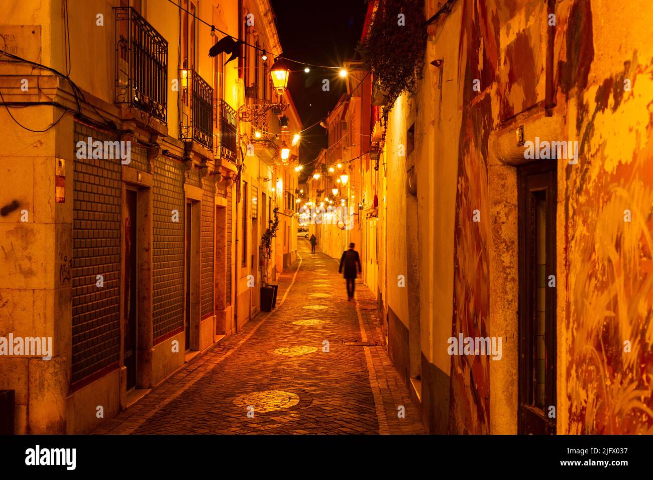 People at night narrow street of traditional architecture illuminated with lanterns, cozy light, Porto, Portugal Stock Photo