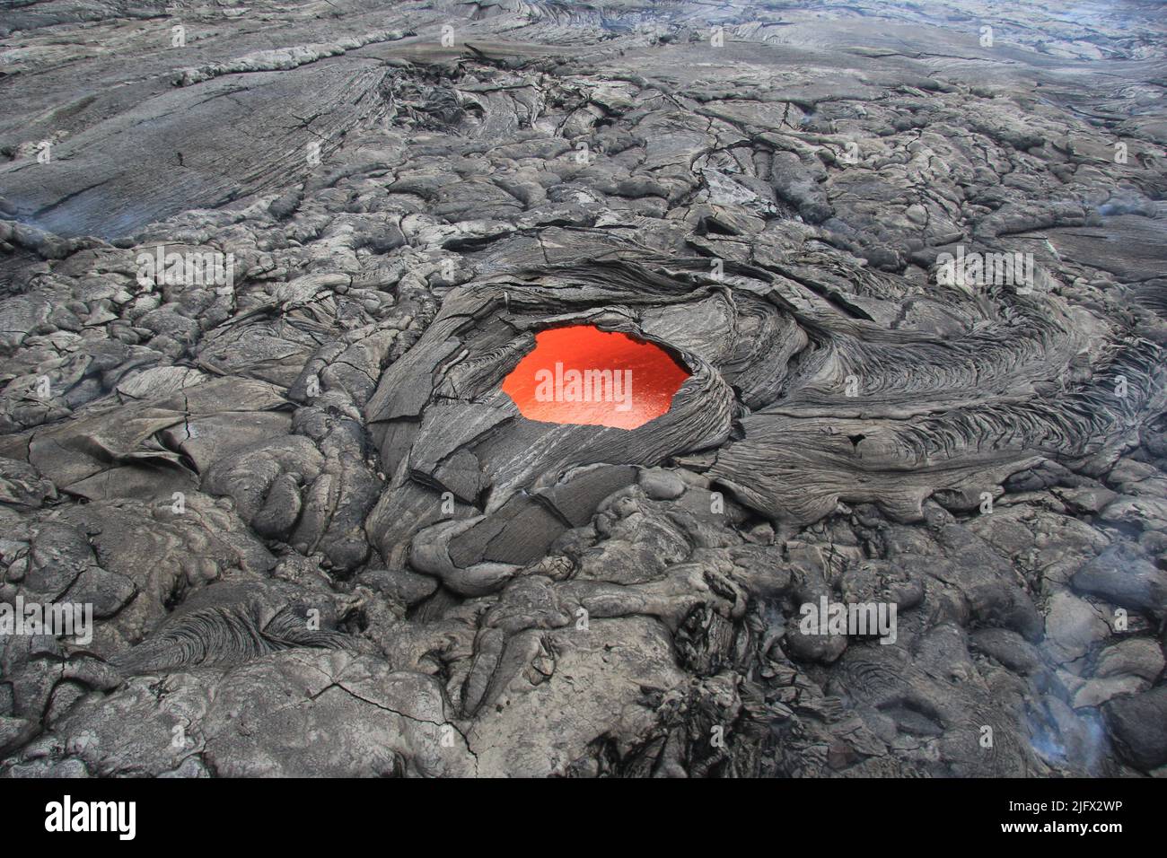 A standalone  lava skylight on the  Puʻu ʻŌʻō crater at K?lauea, Hawaii. The skylight is about 6m (20 ft) across and the lava stream is flowing toward the upper right side of the photo. Credit: USGS Stock Photo