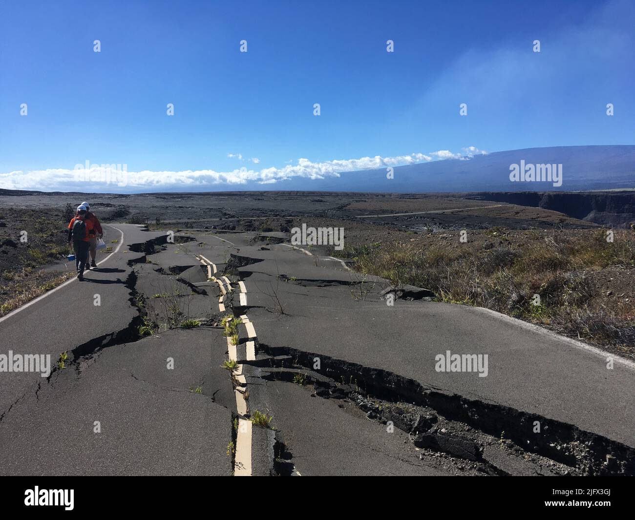 Volcanism  amage to roads.  In this photo, a US Geological Survey field crew hikes along a portion of Crater Rim Drive road, K?lauea, Hawaii. The road was damaged during the 2018 K?lauea summit collapse. Credit: P.Dotray/USG Stock Photo