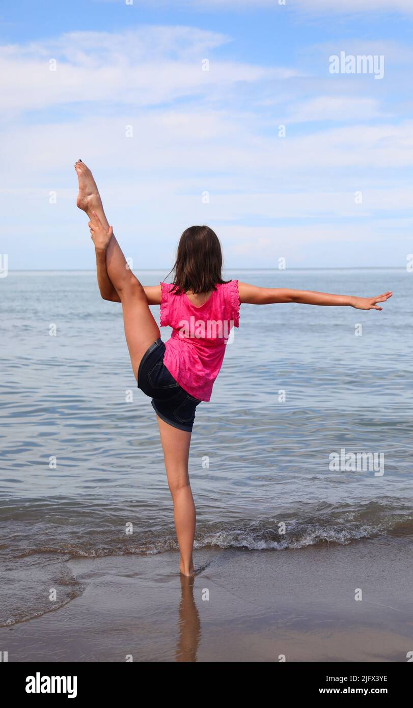 young girl while doing gymnastic exercises and moves her slender leg