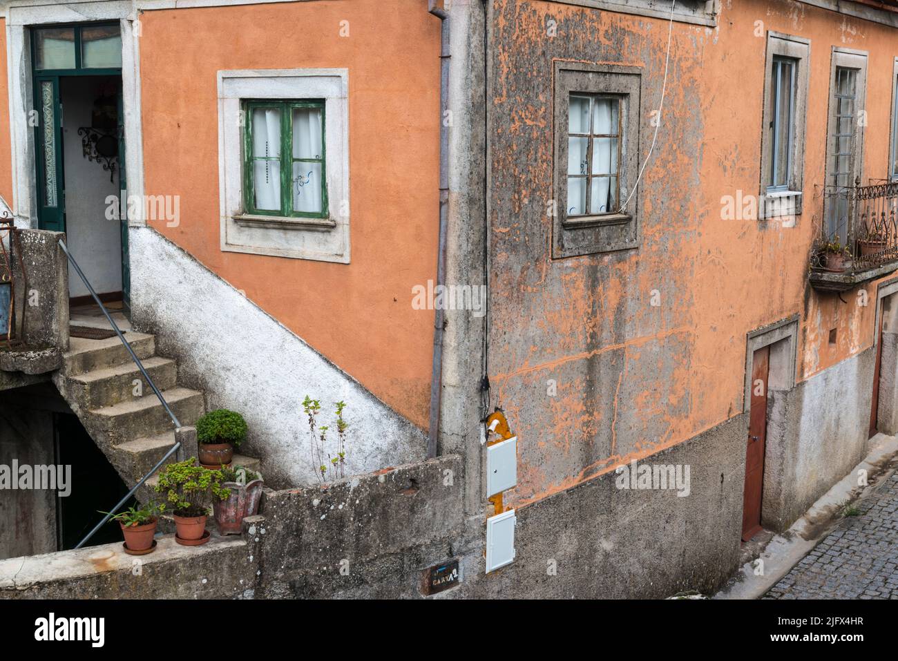 Facade of orange colored shabby house in Sao Paio village. Gouveia district, Portugal Stock Photo