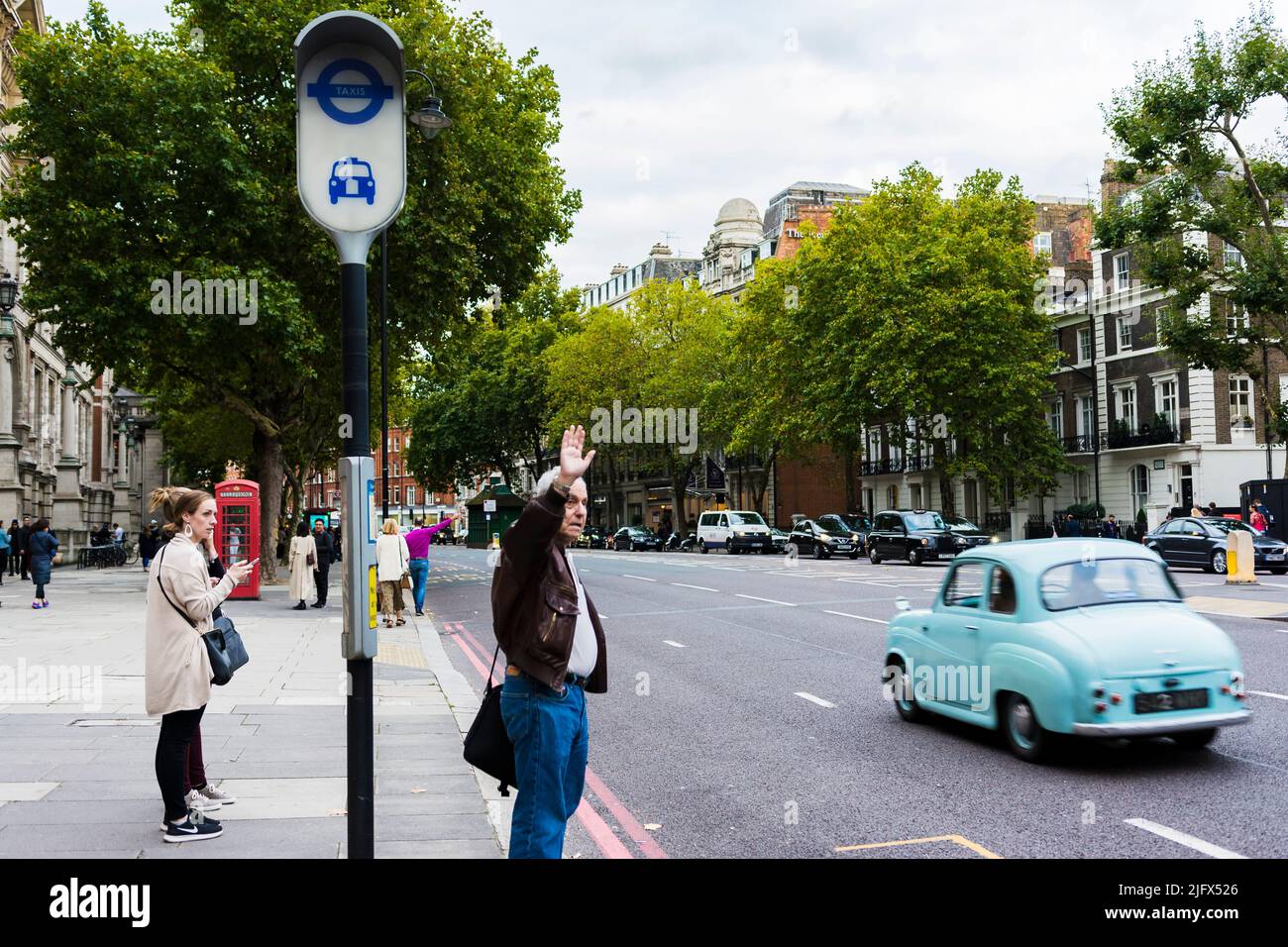 Senior man flagging down a taxi on a London street. London, England, UK, Europe Stock Photo