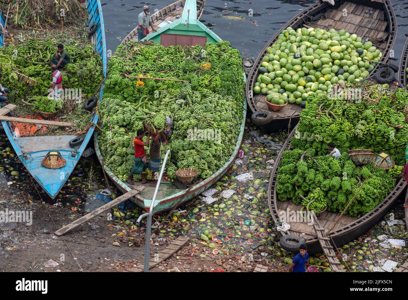 Workers are busy offloading seasonal fruits from boats at Wiseghat in Old Dhaka. Bangladesh Stock Photo