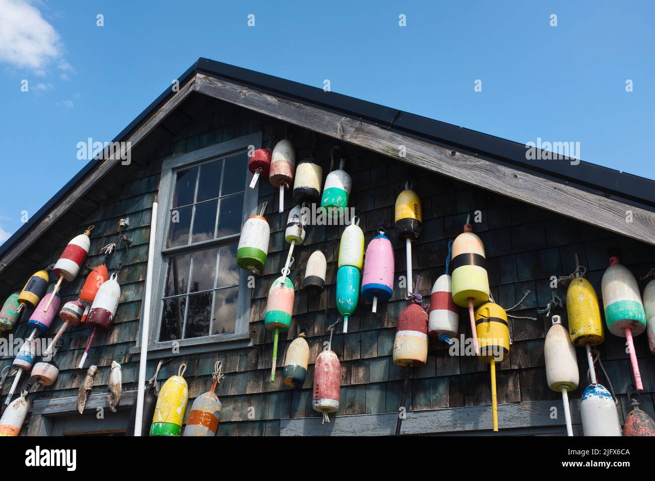 Lobster Trap Buoys hanging on side of Rustic Building Stock Photo