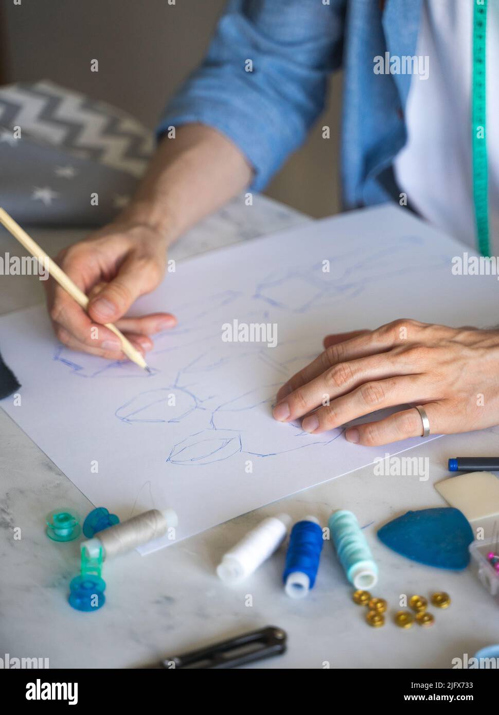 The self-taught tailor's hands are on his sketch. Hand with pencil. A DIY designer draws a sketch for a new costume project. Close up, selective focus Stock Photo