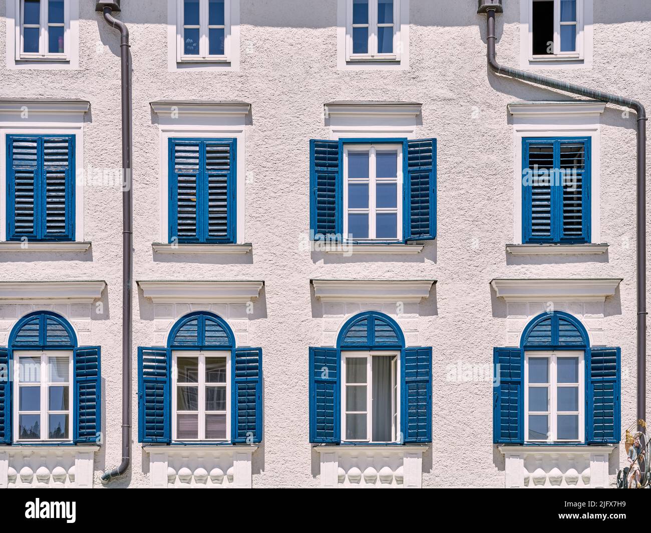 Beautiful house facade with white windows and blue wooden shutters, Hallein, Austria Stock Photo