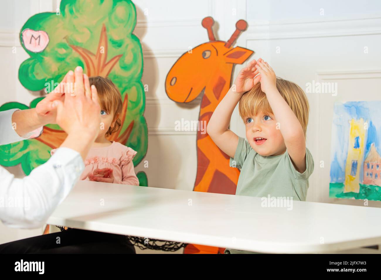 Two kids with teacher therapist play finger development game Stock Photo