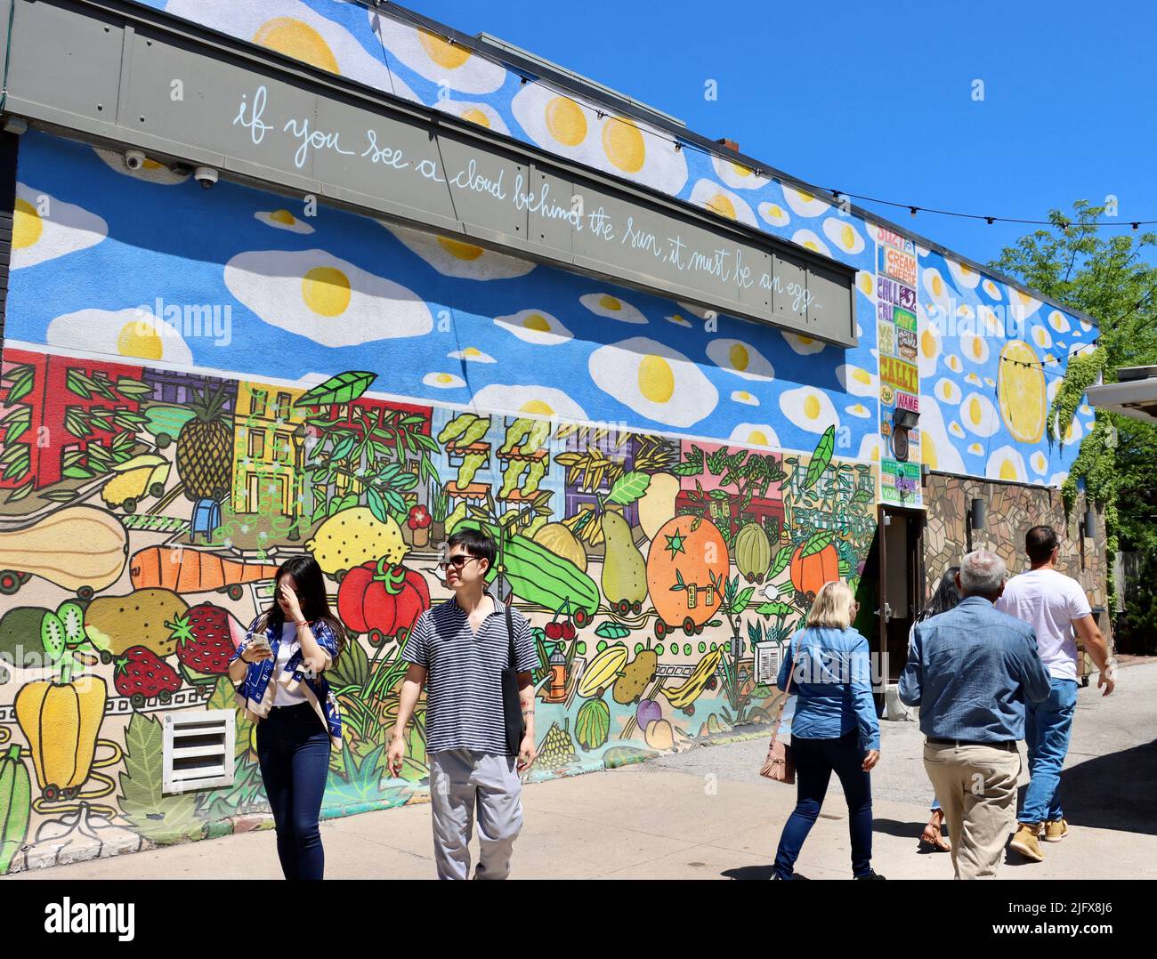People passing a large wall with street art in Cleveland, Ohio in May