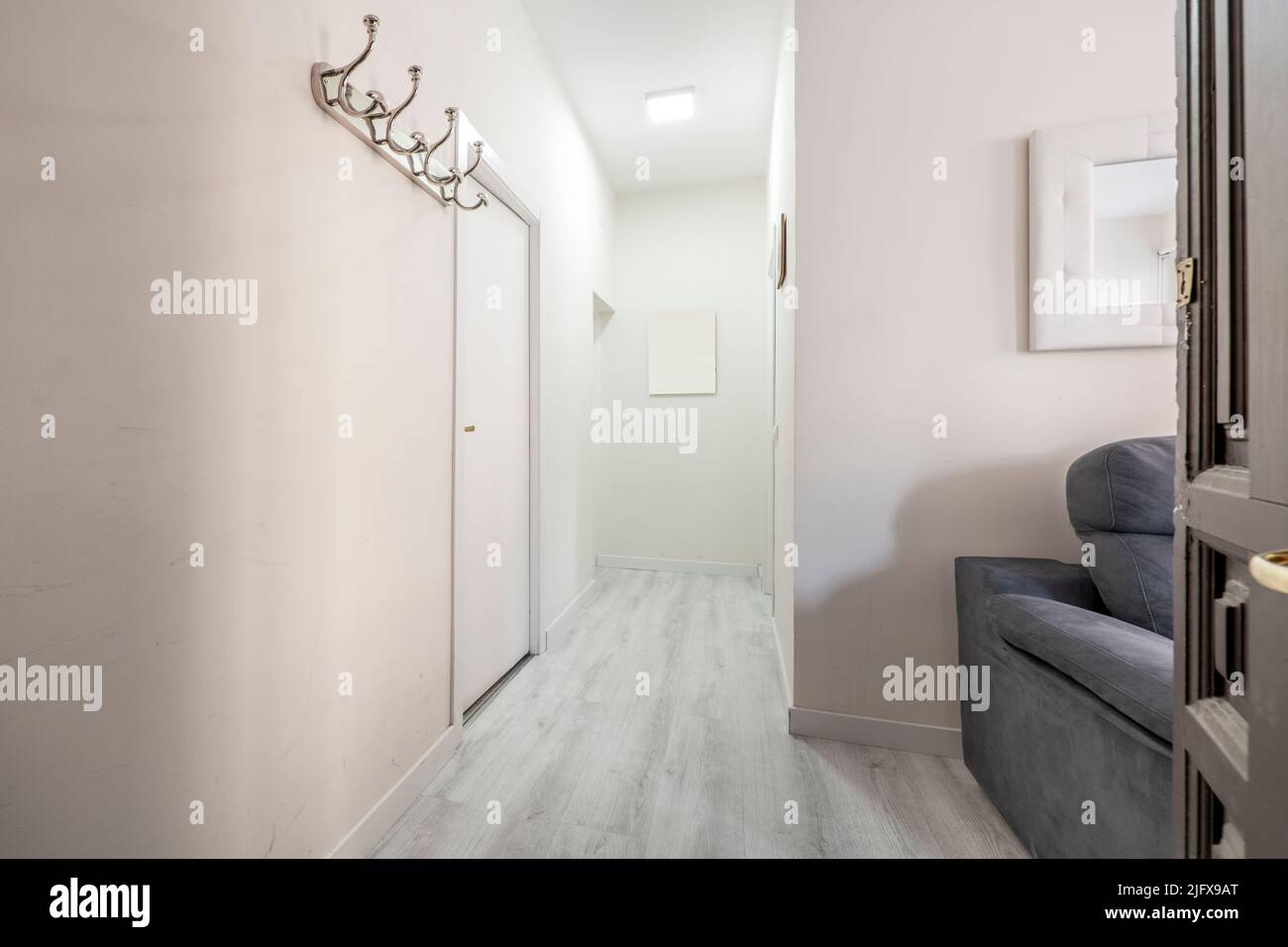 Entrance hall and hallway of a house with light wood parquet, metal