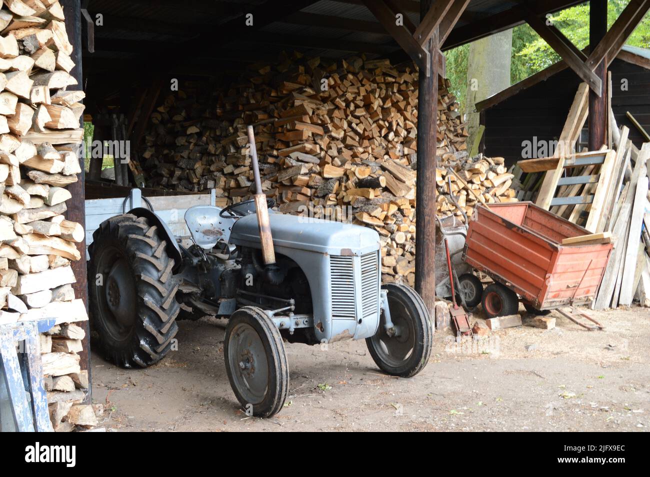 Working antique tractor amid chopped timber from wilnd-blown trees, 16th century Earlshall Castle, Leuchars, Fife, Scotland, July 2022, Open Gardens Stock Photo