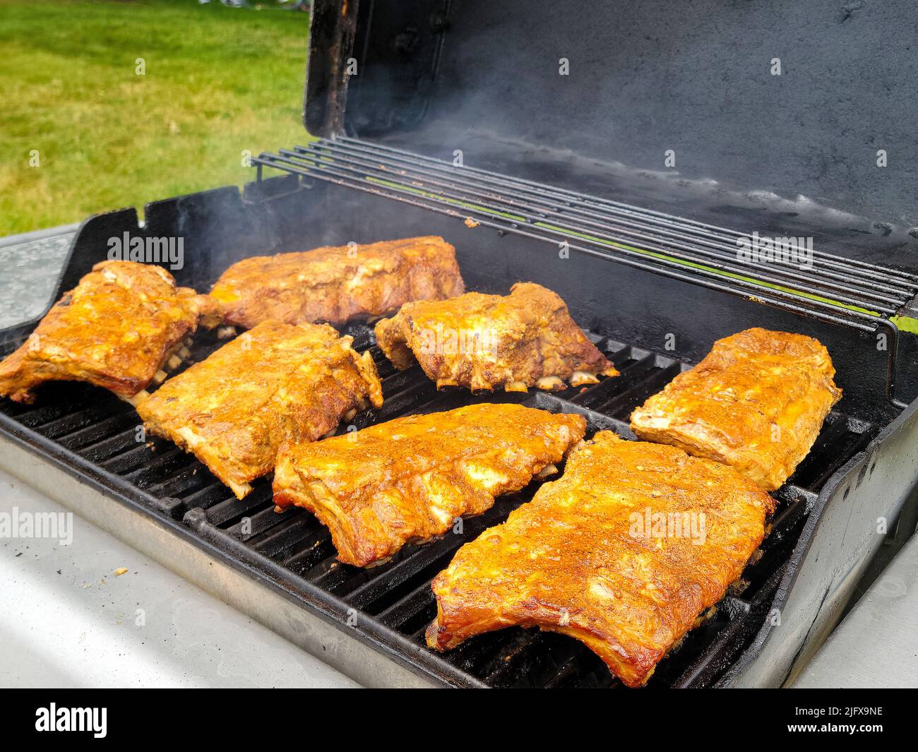 Ribs with dry rub seasoning cooking on an outdoor barbecue grill Stock Photo