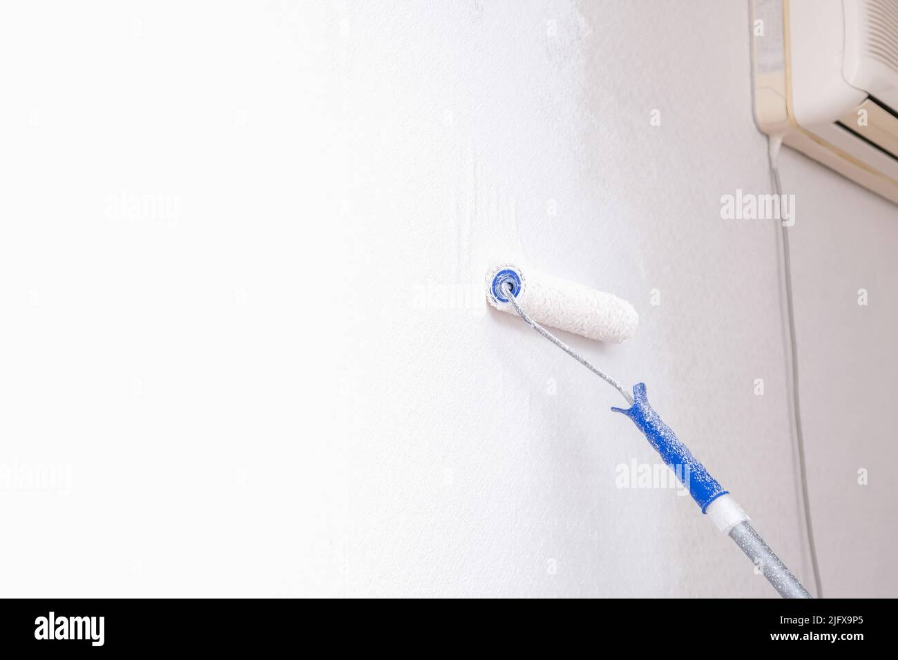A man is painting vinyl wallpaper with a velour roller for painting