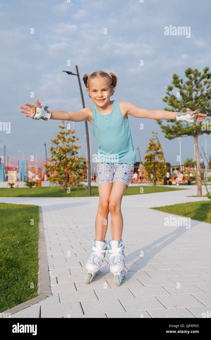A girl in roller skates rides in the park. Stock Photo