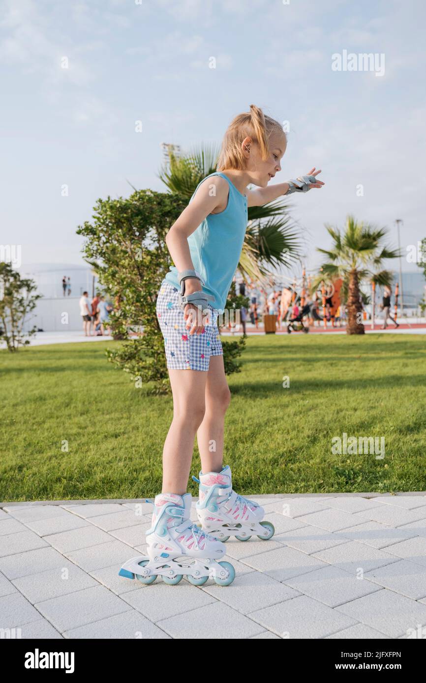 A girl in roller skates rides in the park. Stock Photo