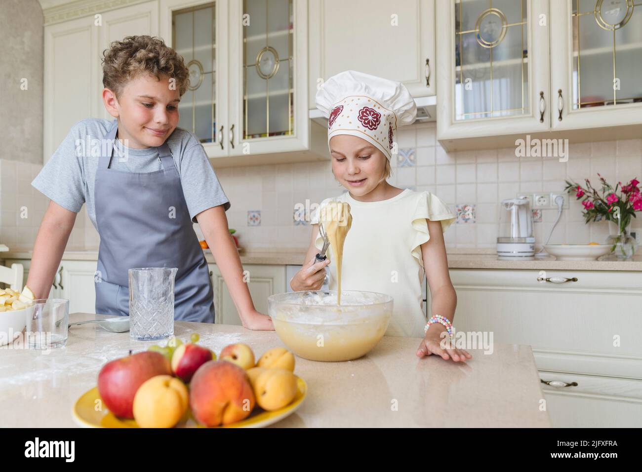 Children in the kitchen are preparing dough for apple pie. Stock Photo