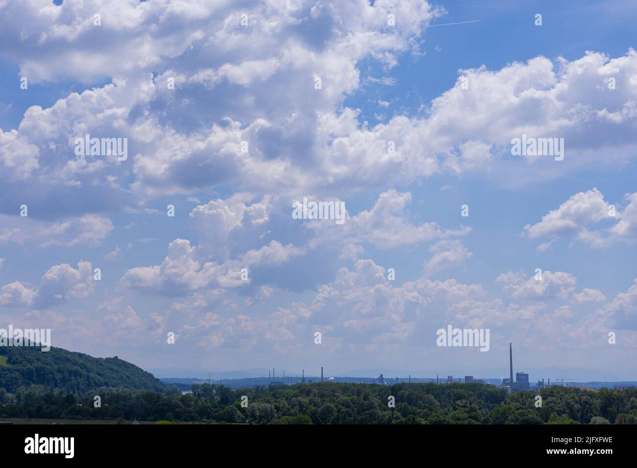 Panoramic view of a factory at the city of linz, austria. Dirty factory in the background of a nice beautiful forest. Contrast concept. Stock Photo