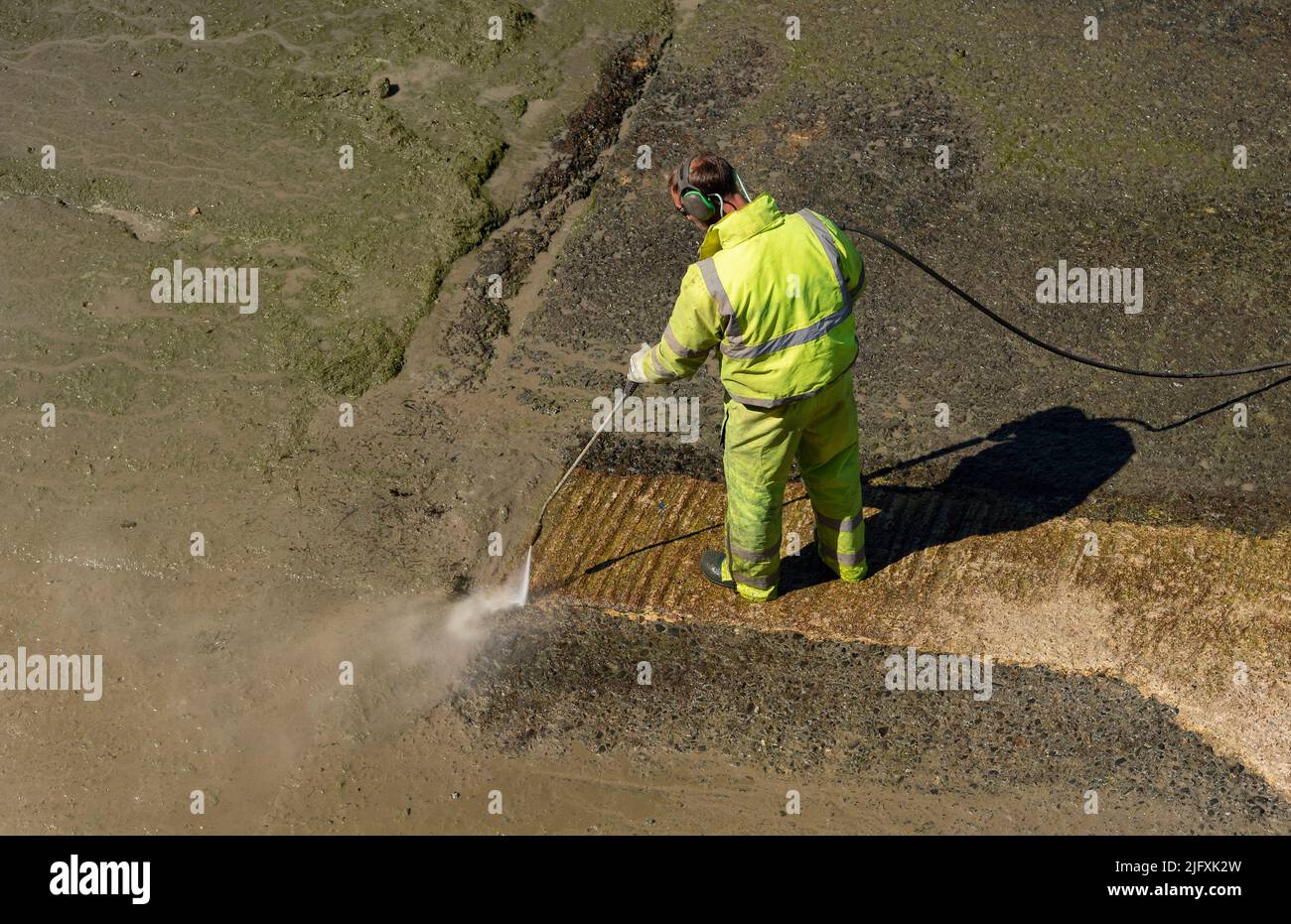 Penzance, Cornwall, England, UK. 2022. Man using a pressure washer at
