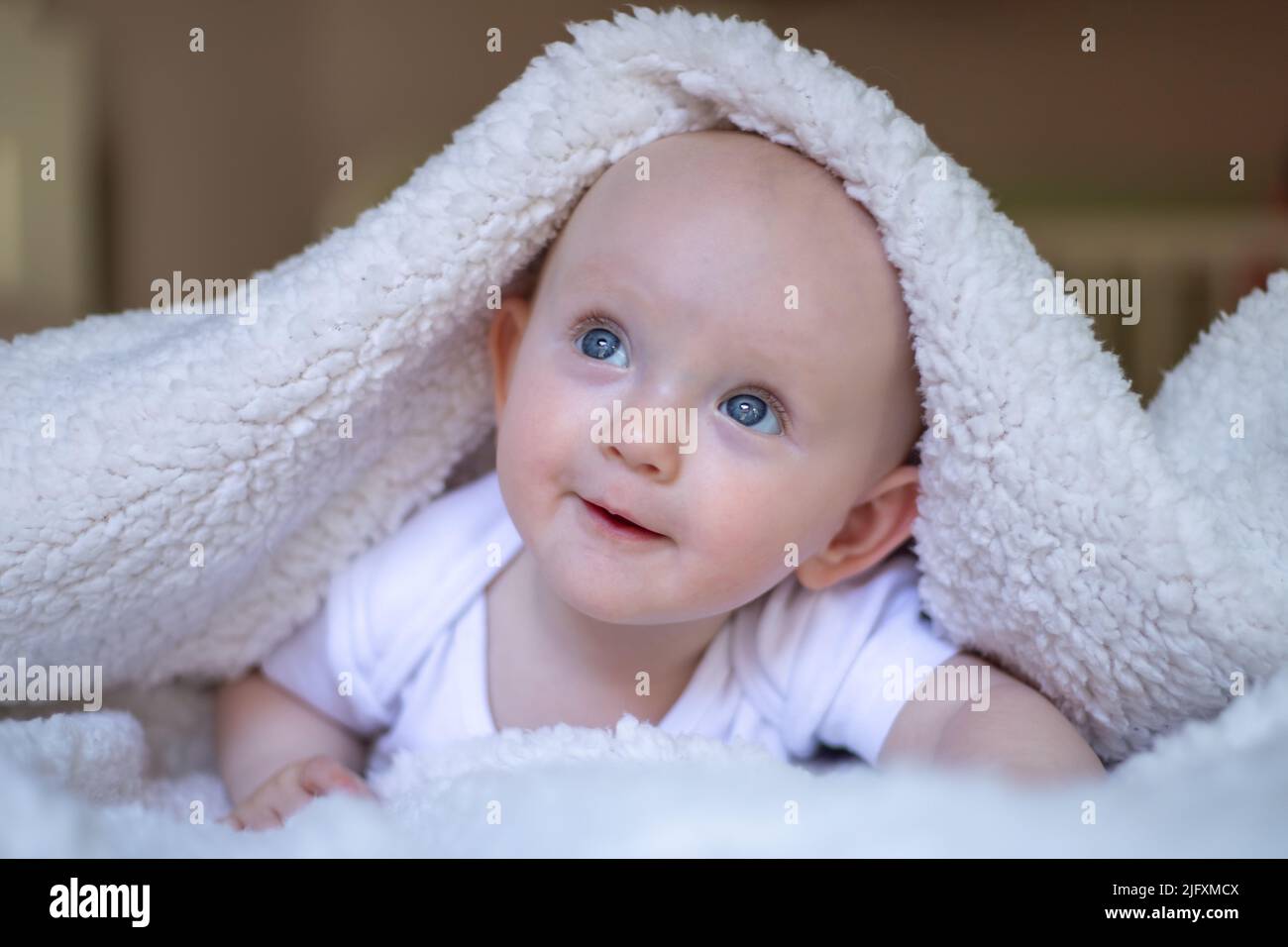 smiling baby looking at camera under a white blanket, towel Stock Photo -  Alamy