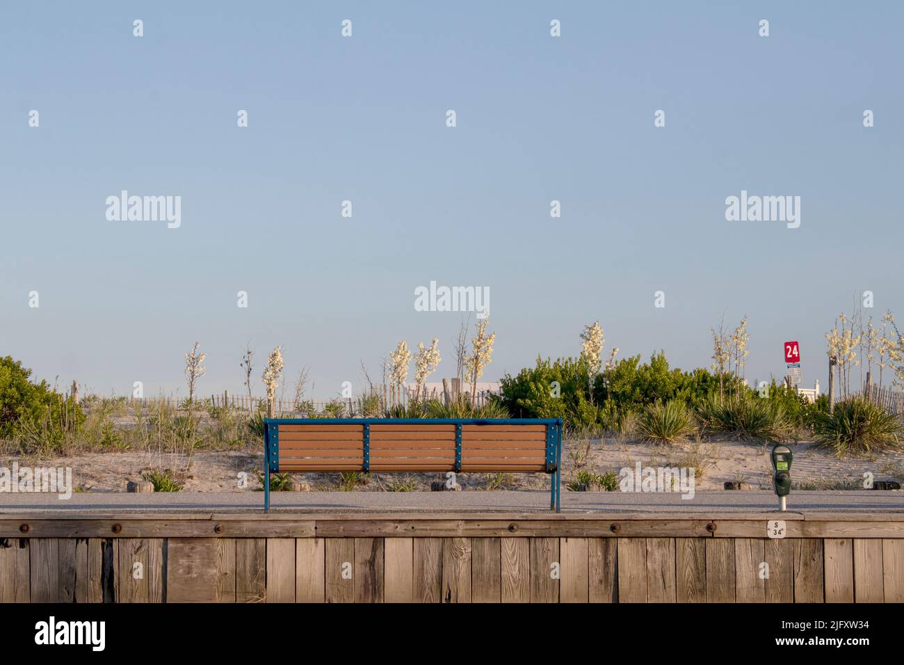 An empty bench overlooks the sand dunes and ocean along the beaches of Cape May New Jersey Stock Photo