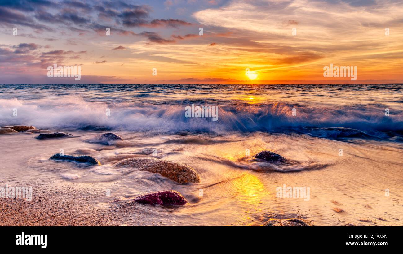 The Sun Rises As A Wave Splashes On A Colorful Tropical Beach High Resolution Stock Photo