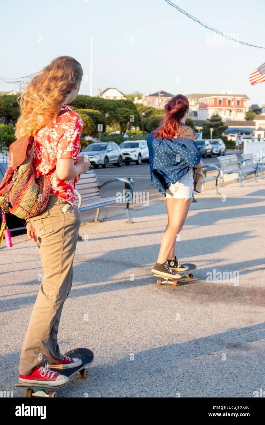 2 females or girls skateboard or longboard along the boardwalk of Cape May New Jersey in the