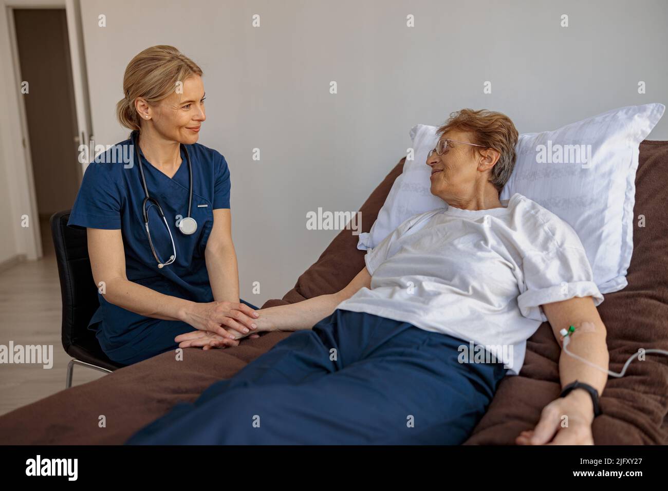 Doctor holding a sick patient by hand supporting her sitting in a