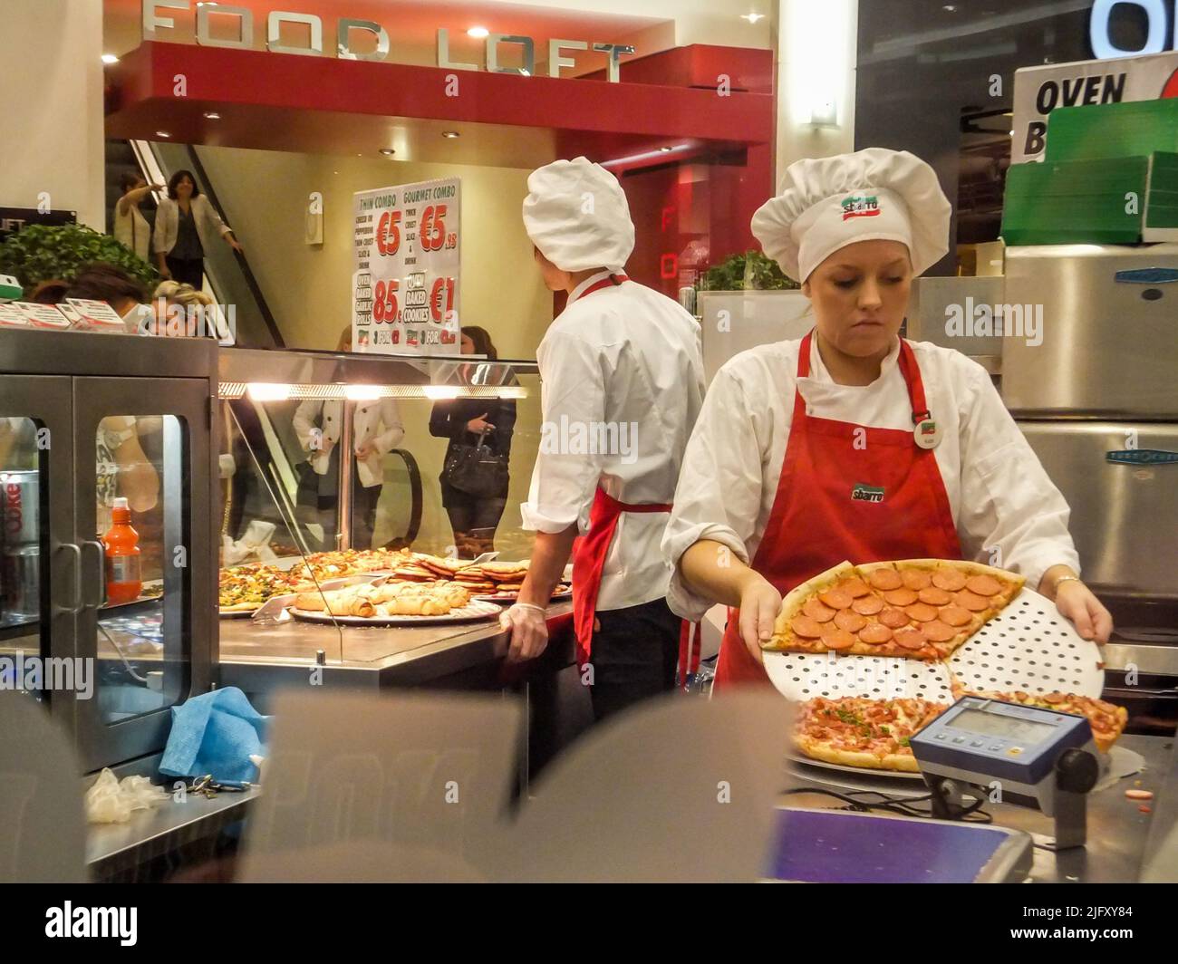 Uniformed employees prepare pizza at Sbarro Pizza in the Jervis Shopping Centre in Dublin, Ireland. Stock Photo