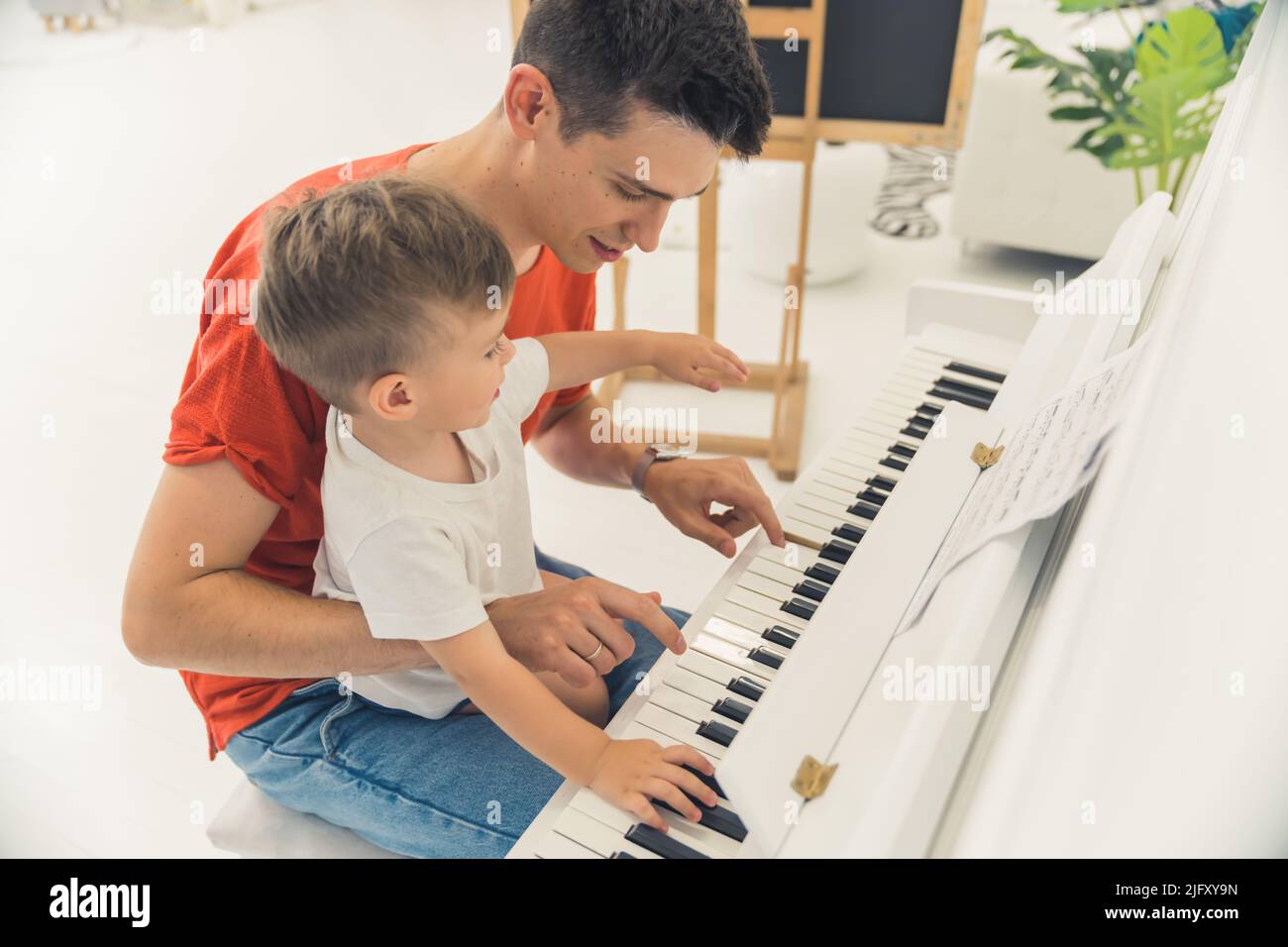 little boy playing the paino with his father, medium shot indoor, family concept. High quality photo Stock Photo