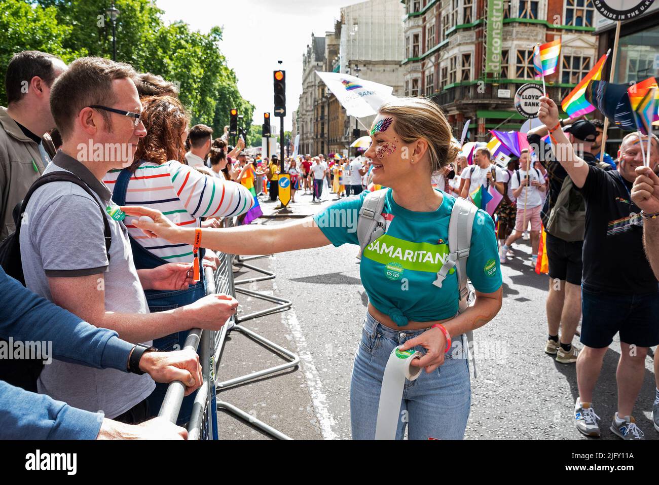 Piccadilly, London, UK. 2nd July 2022. London Pride March 2022. Celebrating 50 Years of Pride in the UK and following the same central London route taken in 1972. Samaritans Pride Marcher placing sticker on man behind barrier. Credit: Stephen Bell/Alamy Stock Photo