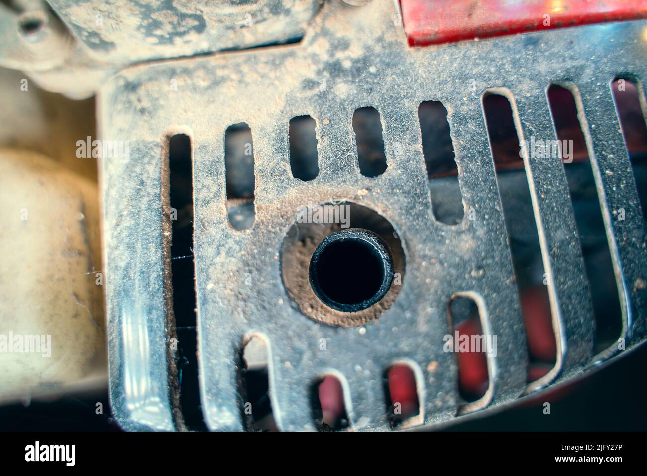 The exhaust pipe of a small gasoline engine in black soot. Protection for hands on the muffler