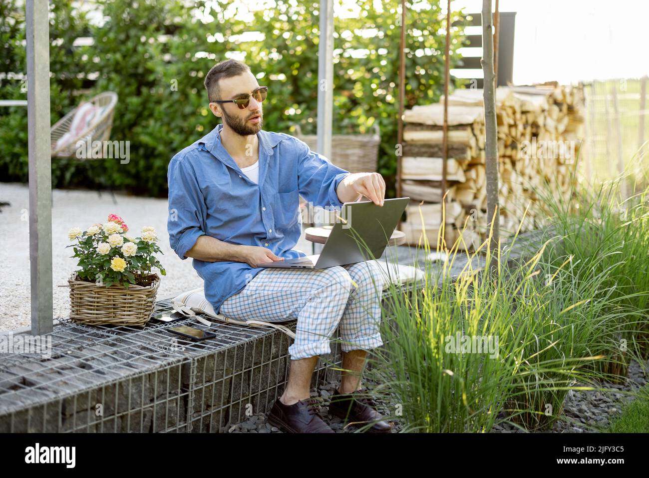 Man works on laptop while sitting at backyard Stock Photo