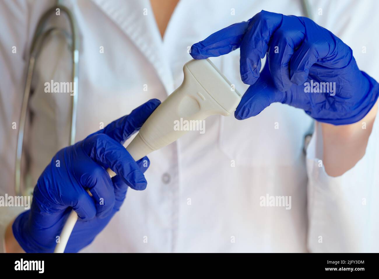 Practitioner in white gown showing ultrasound probe Stock Photo