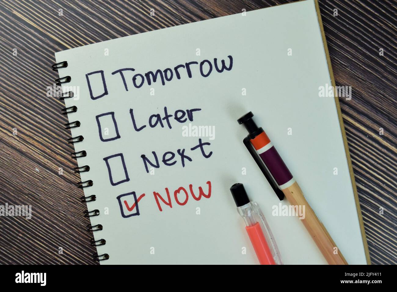 Concept of marking checkbox of now, later, next and tomorrow write on a book isolated on Wooden Table. Stock Photo