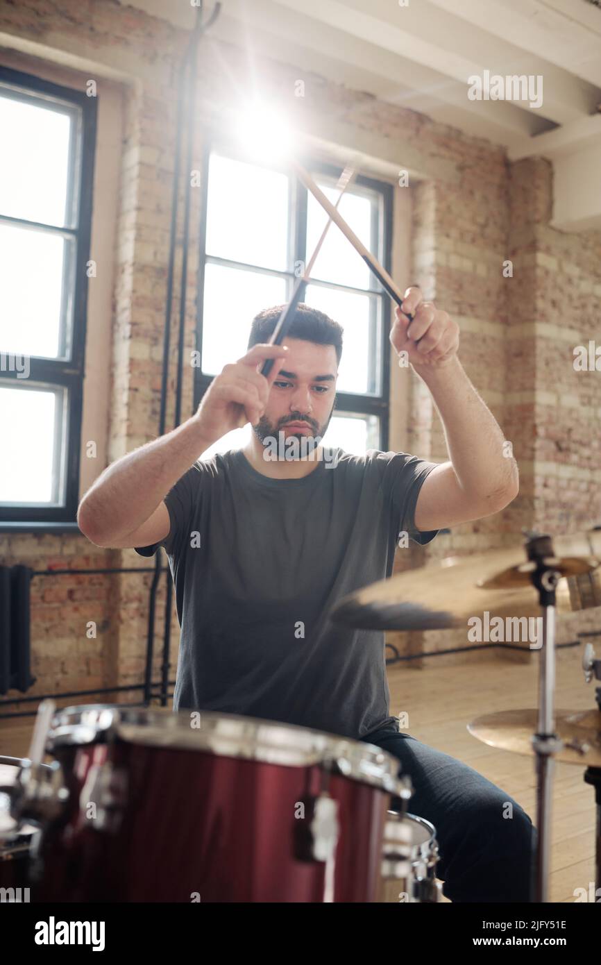 Young drummer concentrating on his play on drums with drumsticks during